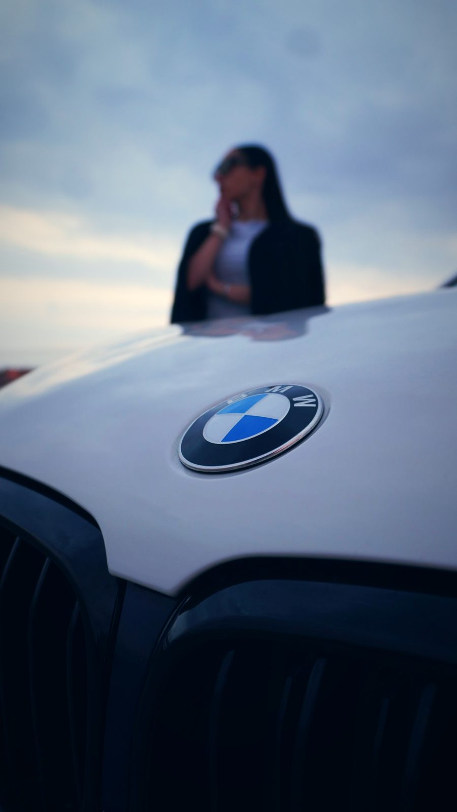 Эмблема BMW в фокусе, девушка размыта