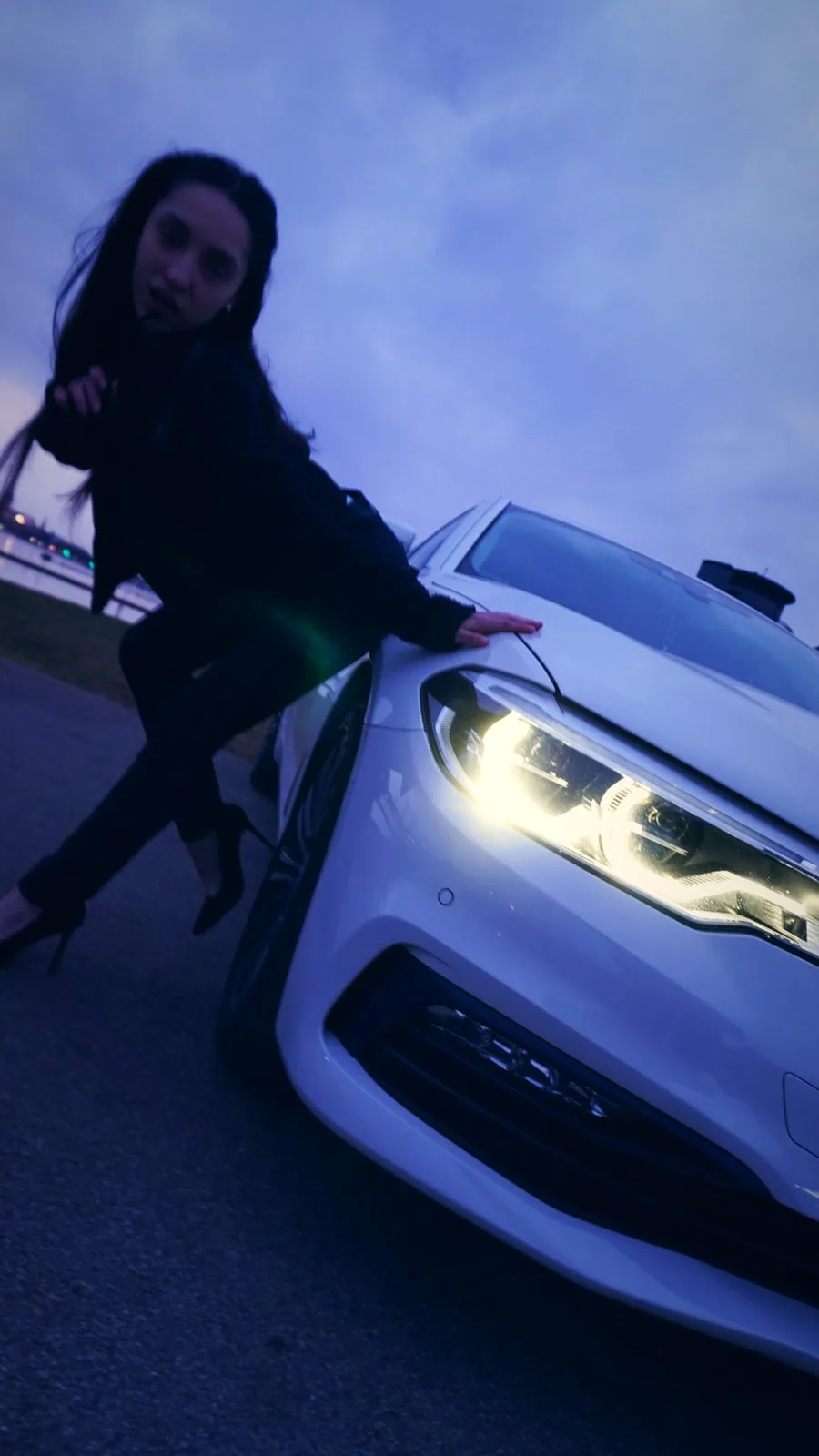 Frau an einem leuchtenden BMW-Scheinwerfer mit Lens Flare