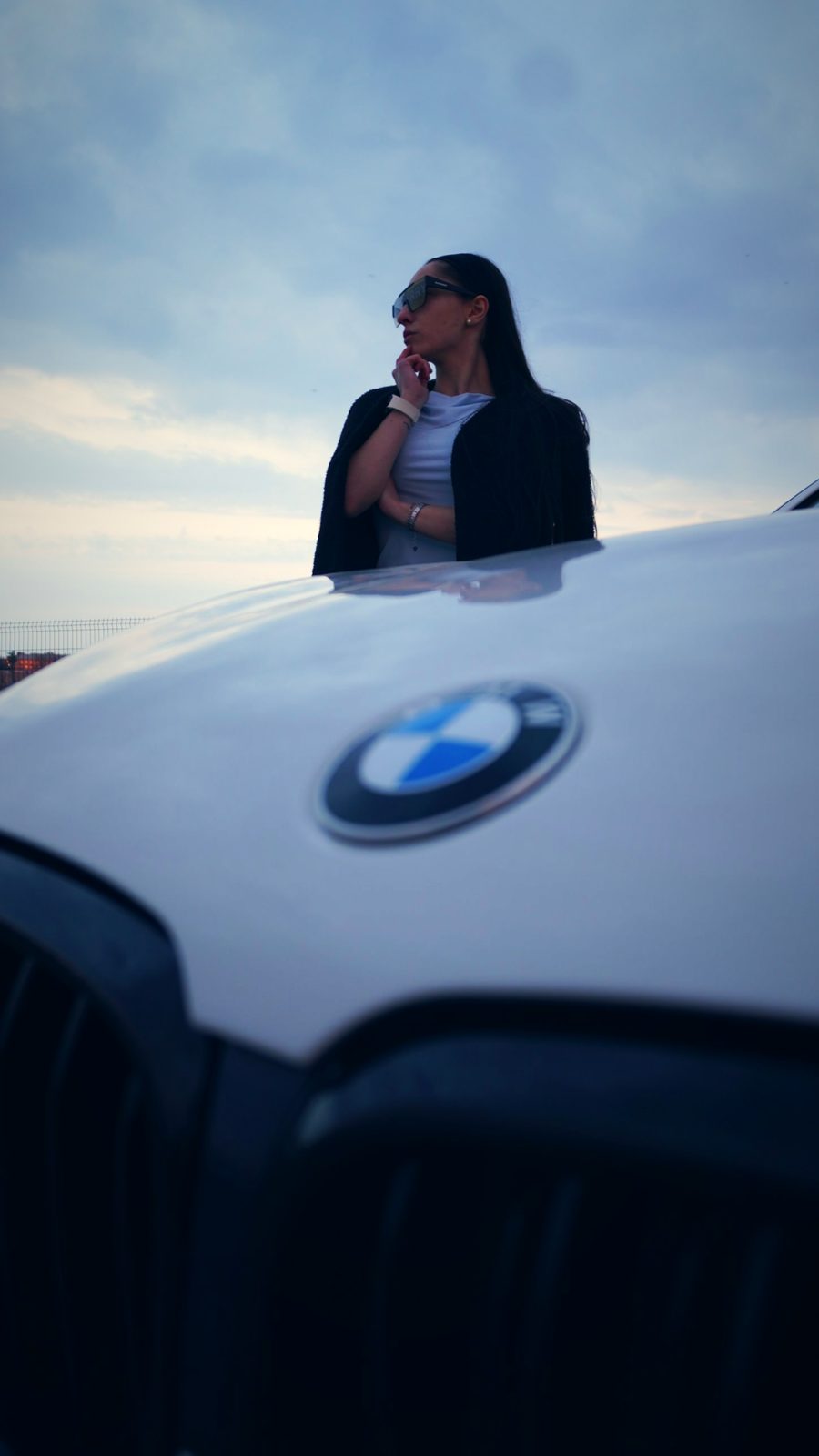 Девушка за капотом BMW, в фокусе