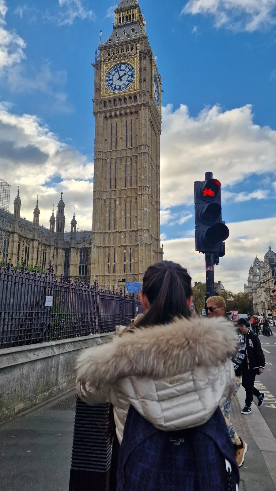 Big Ben in London, im Vordergrund eine Frau mit Fellkapuze