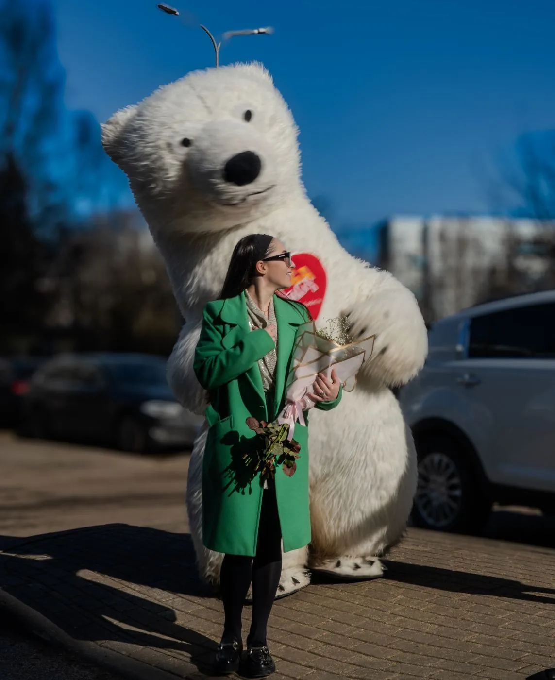 Frau mit Blumen und einem riesigen weißen Teddybären