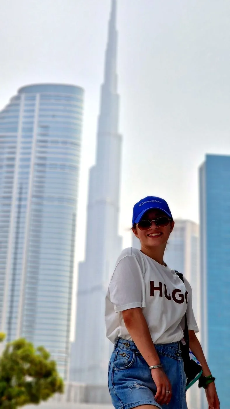 Frau mit blauer Mütze vor den Wolkenkratzern von Dubai