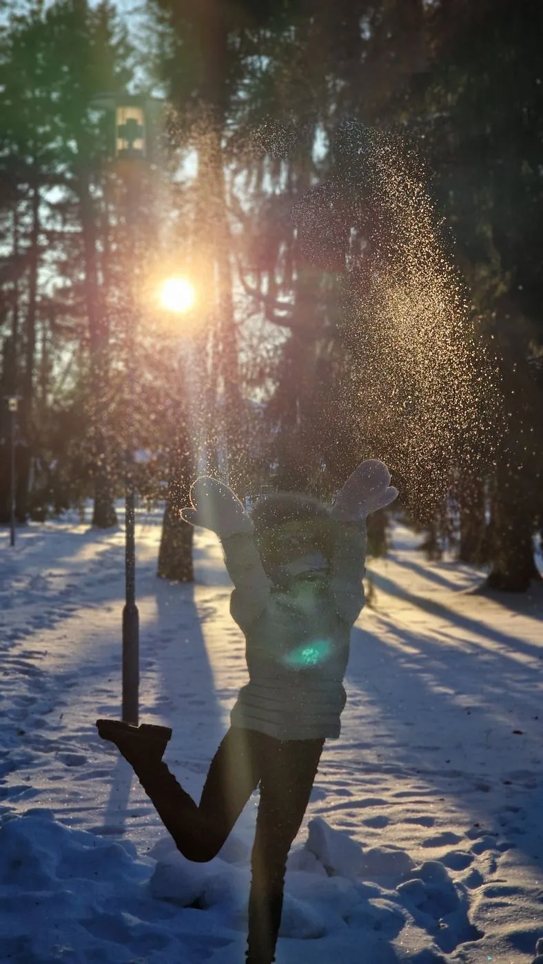 Frau springt und wirft Schnee gegen die Sonne